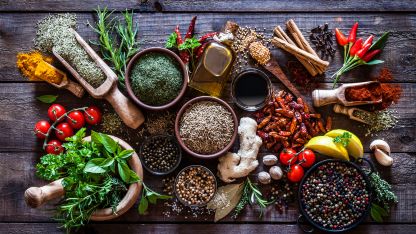 A variety of spices and herbs arranged on a rustic wooden table, showcasing vibrant colors and textures.