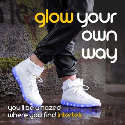 A closeup of a pair of white sneakers with lights along the soles being worn in the rain